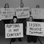 Photograph of people holding sexual assault awareness signs.