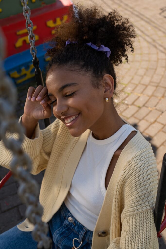 Photograph by Ron Lach: https://www.pexels.com/photo/cute-black-teenage-girl-sitting-in-carousel-seat-with-eyes-closed-and-smiling-9653763/. Public Domain.